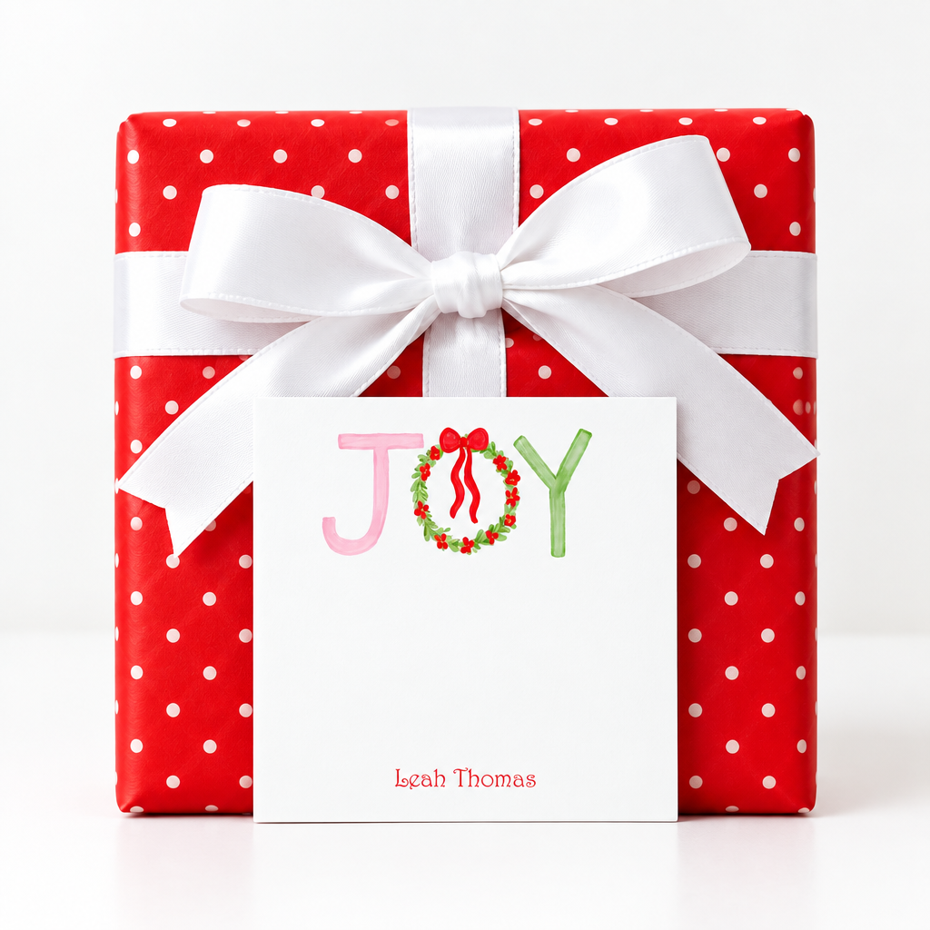 Christmas JOY notepad propped against a red polka-dot present